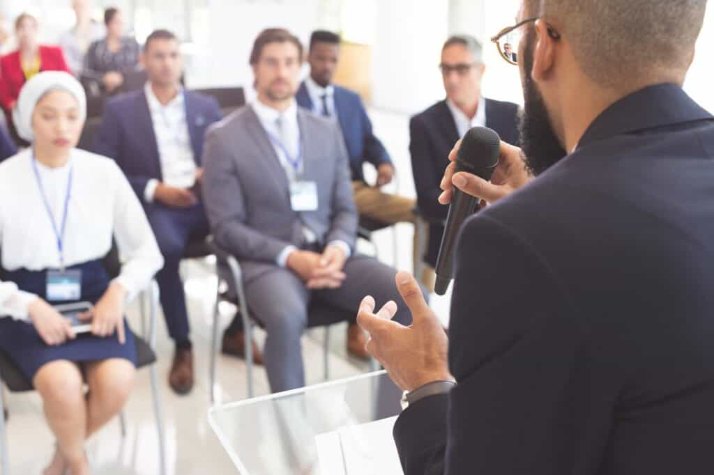 Условия выступления в бизнес-клубе Casemeeting 7 Male speaker speaks with microphone to business people in a business seminar
